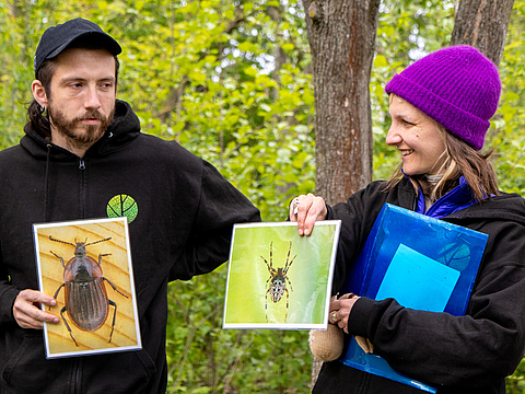 Sophie Sonnemann und Leonard Kraut vom MIYA e. V. halten Bilder von Insekten