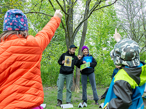 Zwei Kinder heben die Hände in einem Workshop, gegenüber stehen zwei Naturpädagogen des MIYA e. V.